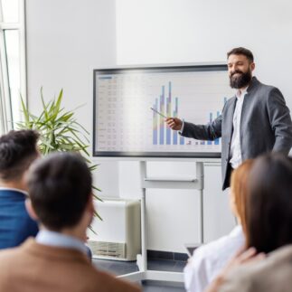 Smiling,Presenter,Standing,Near,Interactive,Board,And,Giving,Presentation,On
